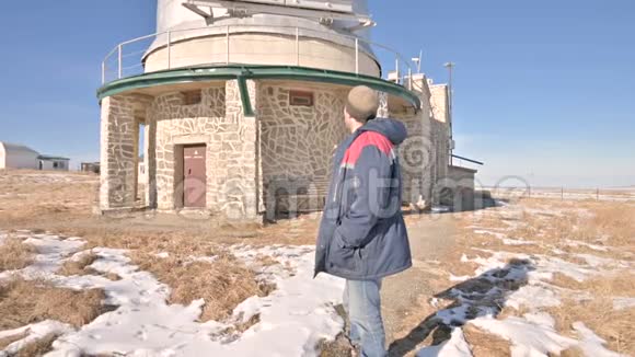 一位穿着牛仔裤和保暖制服的男性研究员在一个冬天阳光明媚的日子里在一个科学建筑的背景下视频的预览图