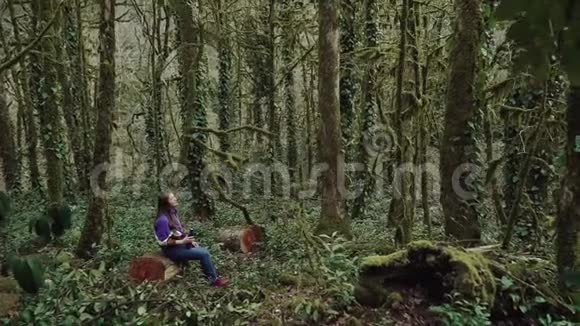 脆弱的女孩正躺在一个茂密的树桩上长满了苔藓和沼泽森林女孩手里拿着一个热水瓶视频的预览图