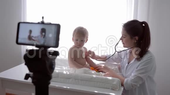 视频课博客作者母亲医学检查儿子使用听诊器并领导现场学习广播在智能手机上视频的预览图