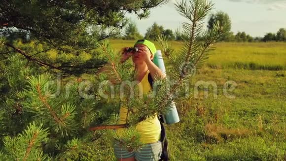 一位女游客站在森林的空地上透过望远镜看下一步该去哪里视频的预览图