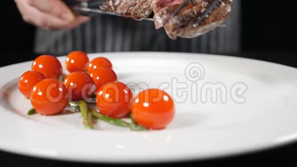 一片炒肉配上樱桃番茄和微绿色放在白色盘子里烤烤牛排特写视频的预览图