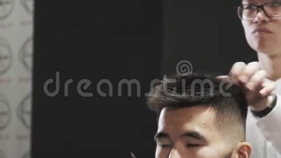亚洲美容师在眼镜梳理头发给客户在沙龙视频的预览图