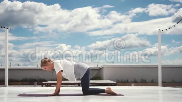灵活的女人在云和蓝天的背景下缓慢地做瑜伽视频的预览图