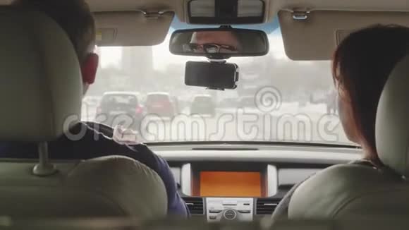 两个人在车里男人开着车女人转过身来坐着微笑挥动她的手视频的预览图
