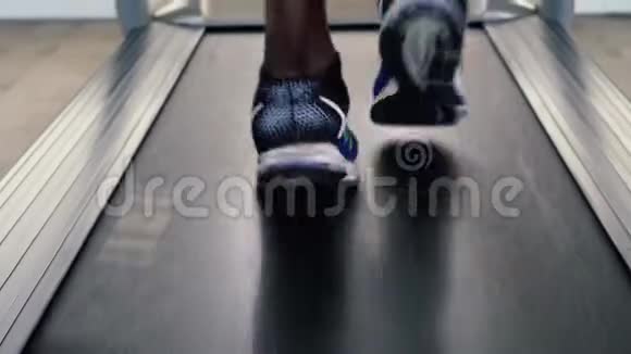 穿着蓝色运动鞋的非裔美国运动员在健身俱乐部的电动跑步机上锻炼不要脸的男跑步者视频的预览图