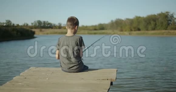 小男孩渔夫在湖上的鱼竿上钓鱼户外视频的预览图