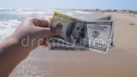 在海浪背景下拿着300美元钞票的女孩视频的预览图