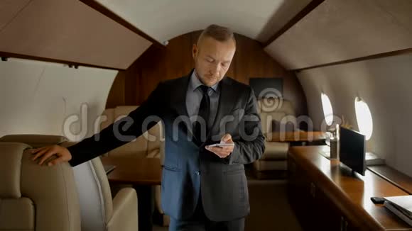 企业家在昂贵的商务喷气式飞机内带电话的肖像视频的预览图