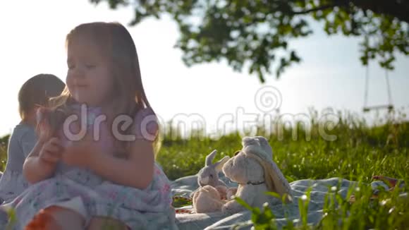 两个小女孩正坐在一片绿色草地中间的野餐封面上视频的预览图