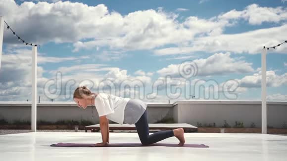 灵活的女人在云和蓝天的背景下缓慢地做瑜伽视频的预览图