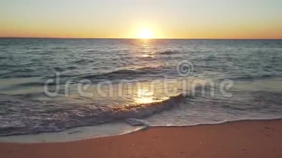 日落于海滩平静的海浪和沙滩在前景视频的预览图