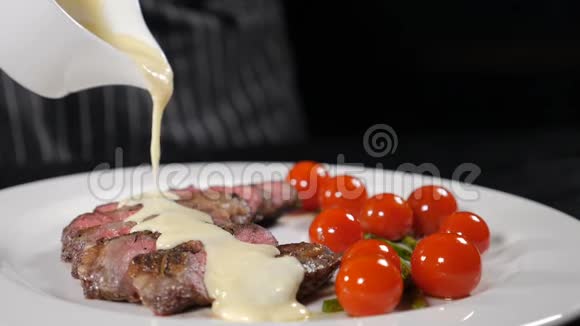 烤牛排上浇着美味的酱汁白色盘子上配上樱桃番茄厨师烹饪美味可口视频的预览图