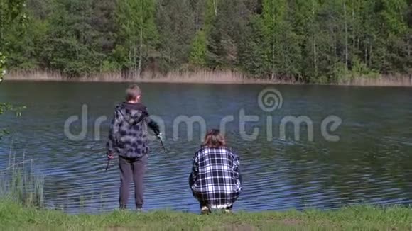 在春暖花开的日子里妈妈和儿子在森林附近的河岸上休息后景视频的预览图