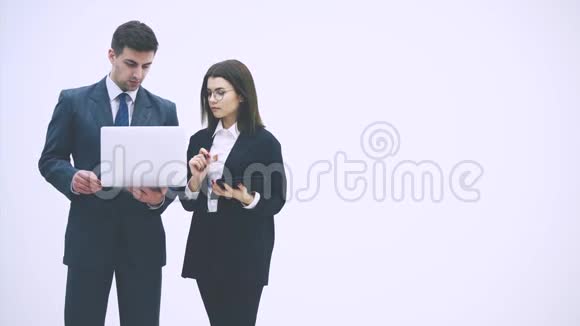 年轻的商业夫妇站着拿着数字平板电脑和笔记本电脑讨论一个项目视频的预览图