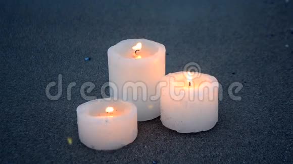三支黄色的小蜡烛靠近蓝色海洋海浪的沙滩视频的预览图
