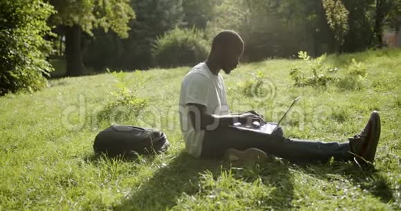 草坪日落时带笔记本电脑的非洲学生视频的预览图