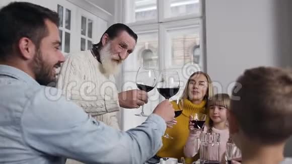 在感恩节庆祝活动中老爷爷和所有家庭成员一起微笑着碰杯视频的预览图