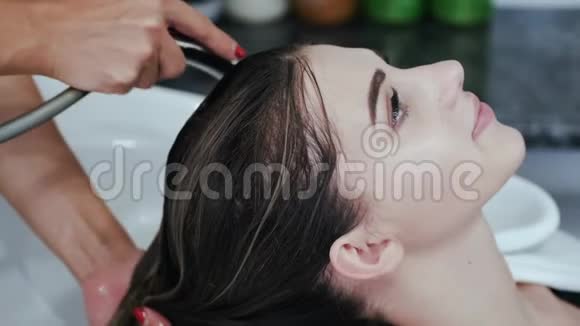理发师在美容院用白色水槽洗女孩的头视频的预览图