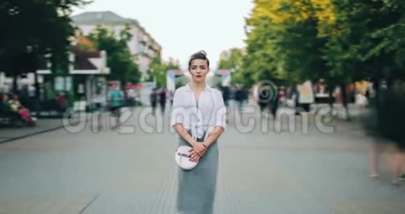 严肃的女人穿着休闲服装站在繁忙的街道上视频的预览图
