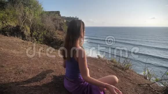 适合年轻女性在山上为海洋练习太阳敬礼瑜伽年轻女性享受冥想和瑜伽健身健身视频的预览图