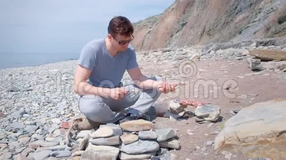 人类正在准备什什利克把肉片放在扦子上坐在有山的海石海滩上视频的预览图