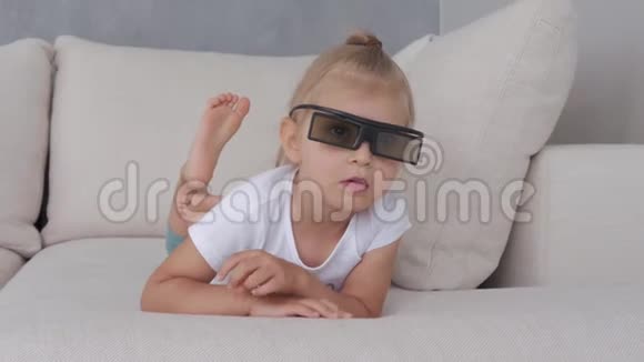 一个戴3D眼镜的小女孩专注地看着电视屏幕视频的预览图