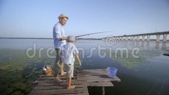 亲子关系快乐爸爸在联合户外度假期间教小儿子在河岸钓鱼视频的预览图