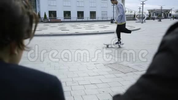 男子单腿拐杖训练与滑板在背景而人们看他在前景视频的预览图