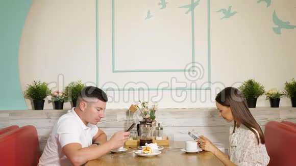 男人和女人在餐桌上用电话在咖啡馆里用甜点视频的预览图