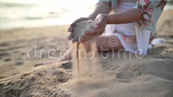 女人拿着沙子放在海滩上夏季旅行和娱乐视频的预览图