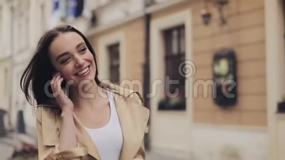有魅力的年轻女孩戴着耳机听音乐用智能手机看着满意的微笑走着瞧视频的预览图