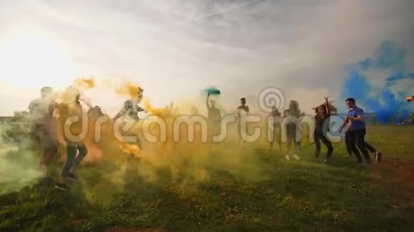 快乐友好的朋友带着发出彩色烟雾的玩具飞机跑过田野视频的预览图