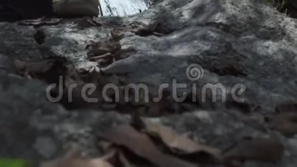 雄鞋站在山上流动的瀑布上的石头上游客在山间瀑布里洗澡帅哥视频的预览图