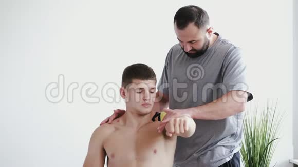 理疗师在临床上将运动学磁带贴在运动员肩上视频的预览图