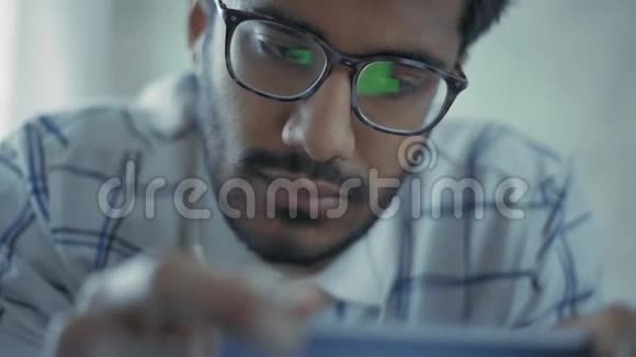 特写镜头带眼镜的印度男人用智能手机看音乐视频视频的预览图