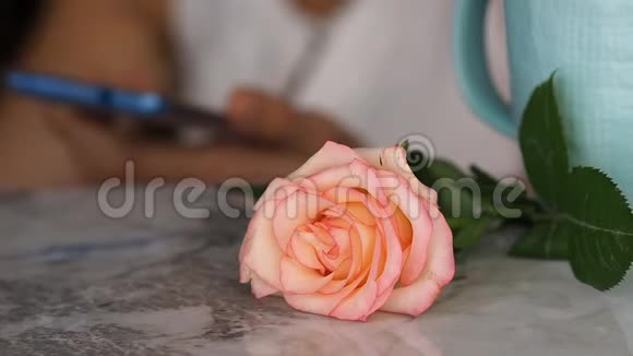 大理石桌上的玫瑰后面有电话的女人视频的预览图
