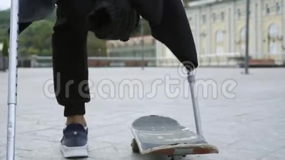 特写男子单腿拄拐训练和做戏法残疾人骑在滑板上动机视频的预览图