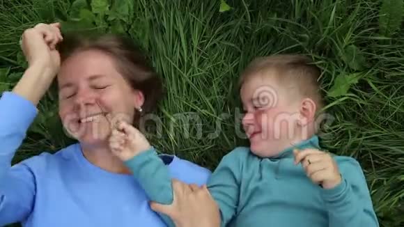 有趣的母子消遣妈妈和三岁的儿子躺在草地上玩得开心视频的预览图