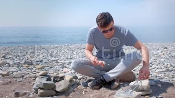 人类正在准备什什利克把肉片放在扦子上坐在靠近篝火的海石海滩上视频的预览图
