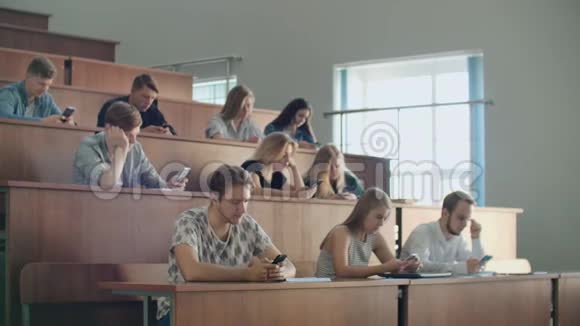 在大学里一堂无聊的讲座学生们看着智能手机的屏幕很多人视频的预览图