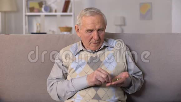 悲伤的老人坐在沙发上手里数着硬币社会不安全视频的预览图