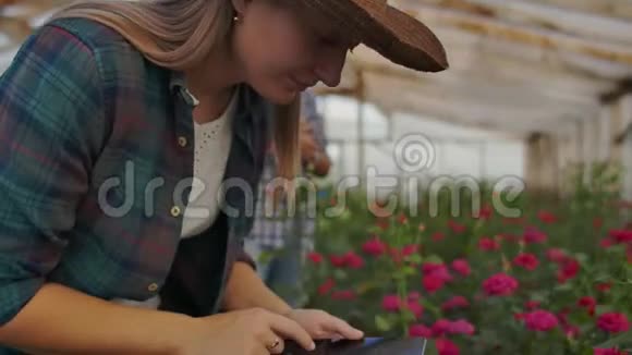 一个拿着平板电脑的女人检查花把手指按在平板电脑屏幕上花卉种植业务视频的预览图