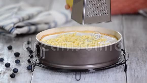 女人手在奶酪蛋糕上用磨粉机磨制糕点面团用碎奶酪做的视频的预览图