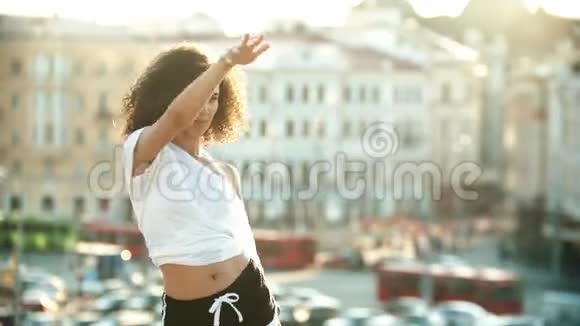 一位年轻的调情女子在屋顶上表演迷人的舞蹈日落视频的预览图