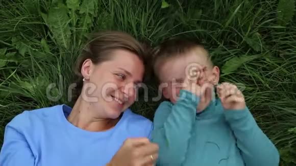 母亲和儿子躺在草地上玩得很开心笑得很开心视频的预览图