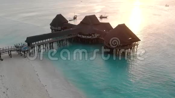 日落时分桑给巴尔Nungwi海滩上美丽的茅草高跷屋蓝色印度洋鸟瞰视频的预览图