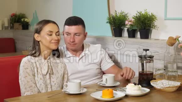 男人在咖啡馆里用茶和蛋糕亲吻女伴视频的预览图
