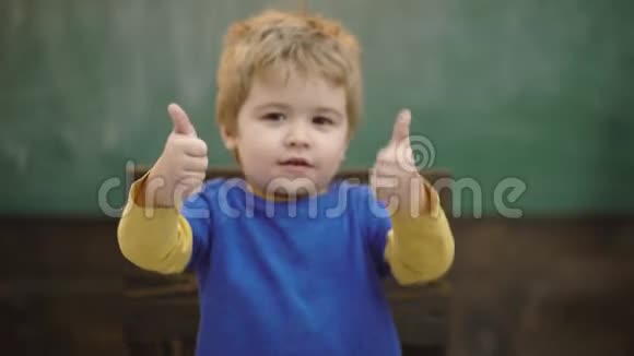 男孩在绿色学校董事会的背景下竖起大拇指有选择的焦点回学校去学习概念视频的预览图