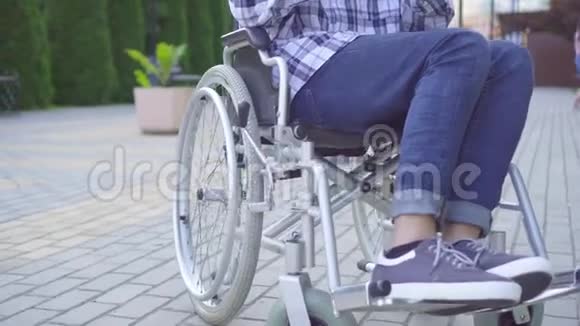 年轻的亚裔男子在公园的轮椅上致残使用智能手机视频的预览图