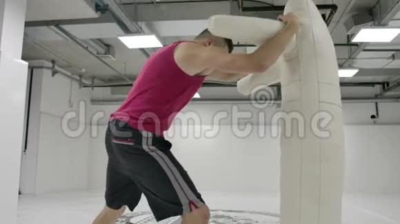 一个拳击手在健身房中缓慢地进行膝盖踢和假人投掷视频的预览图